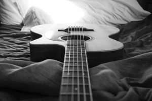 Guitar laying on sheets looking down the length of the guitar fretboard